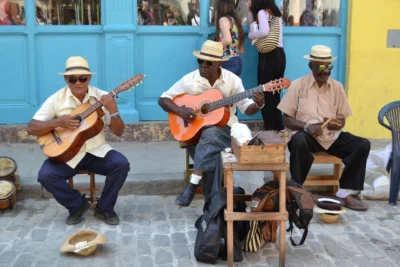 Guía del español cubano Músicos tocando instrumentos tradicionales cubanos, como bongós, trompetas y claves, interpretando son y rumba.